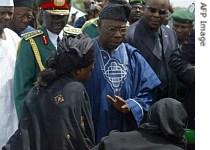 Nigerian President Olusegun Obasanjo (C) accompanied by Chief of Defense Staff General Martin Luther Agwai (L) comforts relatives of the victims at the military national cemetery in Abuja 