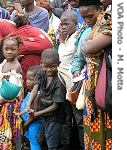 Liberian family lines up to board bus from Touplepleu at UNHCR transit center