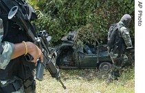 Thai soldiers examine the wreckage of a pickup truck that was hit by a bomb while carrying their colleagues during a patrol on a road in Pattani province, southern Thailand, 13 June 2007