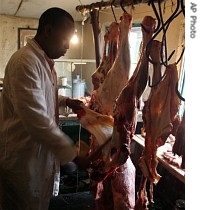 Peter Njoroge slices pieces of beef from a carcass in his makeshift butchery in the Kibera slum in Nairobi, Kenya, 10 July 2007