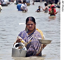 A woman wades through a flooded street to collect food in Sirajgonj, about 104 kilometers (65 miles) north of Bangladesh's capital Dhaka, 03 Aug 2007