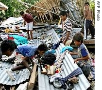 Children hunt for clothes after their village of Titiana, where 15 people died, was hit by a tsunami on the outskirts of Gizo island in the Solomon Islands, 05 Apr 2007