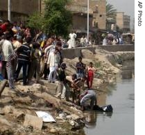 Iraqi men and a policeman try to pull a body from the Euphrates river at Musayyib, Iraq, 23 May 2007