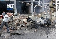 A man pours water to douse a fire on an auto rickshaw where a bomb was planted in Guwahati, India, 26 May 2007