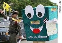 A Thai campaigner (r) dresses as a ballot box stands next to a policement urging people to vote in the upcoming constitutional referendum in Bangkok, 17 Aug 2007